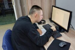 Mężczyzna siedzący przed monitorem komputera.