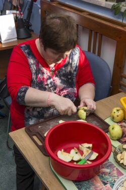 Kobieta krojąca jabłka na desce do krojenia.