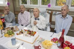 Mężczyźni siedzący przy stole zastawionym słodyczami.
