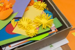 Pudełko z kolorowymi kartkami i kwiatami z papieru.