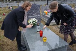 Dwie kobiety stawiające znicze na grobie.