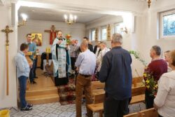 Grupa osób z palmami stojąca w kaplicy i stojący przed ołtarzem duchowny.