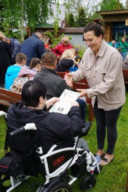Kobieta wręczająca dyplom kobiecie na wózku inwalidzkim.