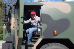 Chłopiec siedzący w kabinie wojskowego samochodu.