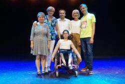 Zdjęcie grupowe. Dziewczynka na wózku inwalidzkim i stojące za nią trzy kobiety i dwóch mężczyzn.