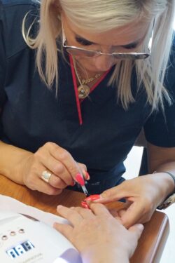 Kobieta malująca paznokcie drugiej osobie.
