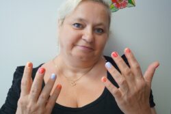 Kobieta pokazująca dłonie z pomalowanymi paznokciami.