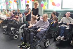 Osoby na wózkach inwalidzkich na dużej sali.