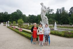 Trzy kobiety stojące przy rzeźbie w parku.