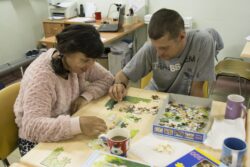 Kobieta i mężczyzna siedzący przy stole układający puzzle.