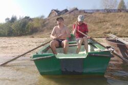 Dwaj chłopcy siedzący w łódce stojącej na brzegu.