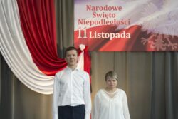 Mężczyzna i kobieta stojący na tle biało czerwonej dekoracji z napisem Narodowe Święto Niepodległości 11 Listopada.