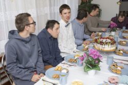 Grupa chłopców siedząca przy zastawionym słodyczami stole.