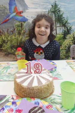 Siedząca przy stole dziewczynka przed którą stoi tort.