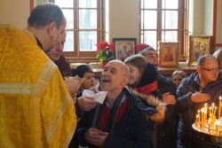 Duchowny udzielający komunii mężczyźnie w cerkwi.