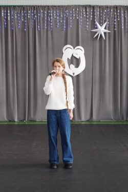 Dziewczyna z mikrofonem w ręku stojąca na dużej sali.