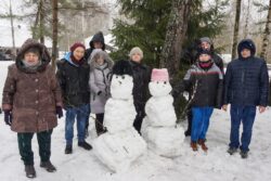 Grupa osób stojąca za dwoma śnieżnymi bałwanami.