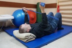 Mężczyzna wykonujący ćwiczenia na materacu w pozycji leżącej na plecach.