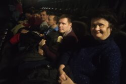 Grupa osób siedząca w fotelach na sali kinowej.