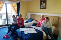 Cztery kobiety siedzące w pokoju hotelowym na łóżkach.