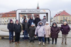 Grupa osób stojąca na placu w centrum miasta przed ramką z napisem dumni z Białegostoku.