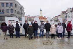 Grupa osób stojąca przed napisem Białystok. 