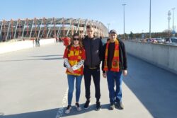 Dziewczyna i dwóch chłopaków stojący przed stadionem.